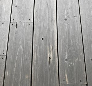 Close-up of weathered gray wooden planks with visible knots and cracks.